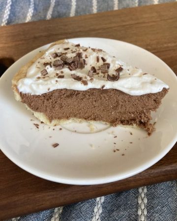 Slice of chocolate pie with whipped cream on a white plate