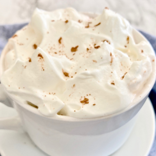 white ceramic mug filled with whipped cream and topped with cocoa powder