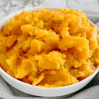 cooked butternut squash in a white bowl on a grey background