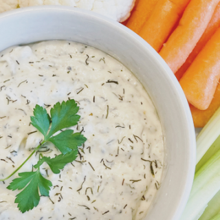 sour cream dill dip in a bowl surrounded by vegetables