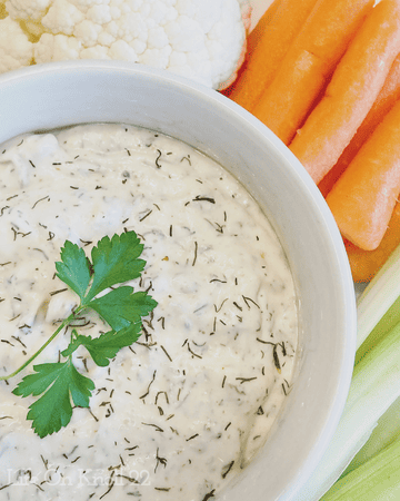 sour cream dill dip in a bowl surrounded by vegetables