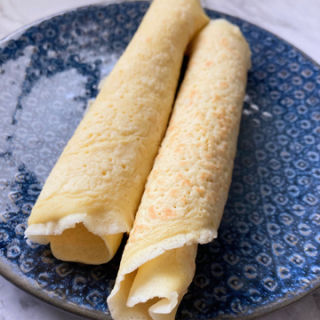 rolled sourdough discard crepes on a blue plate