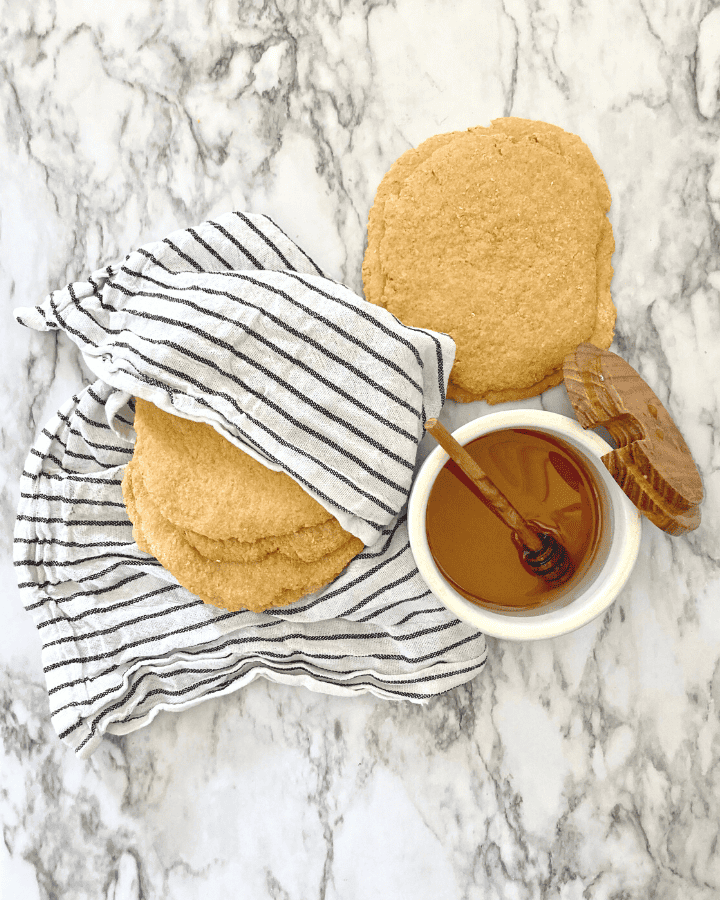 whole wheat flatbread wrapped in a towel by a jar of honey