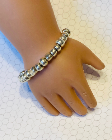 18 inch doll hand with a silver bead bracelet on it's wrist.