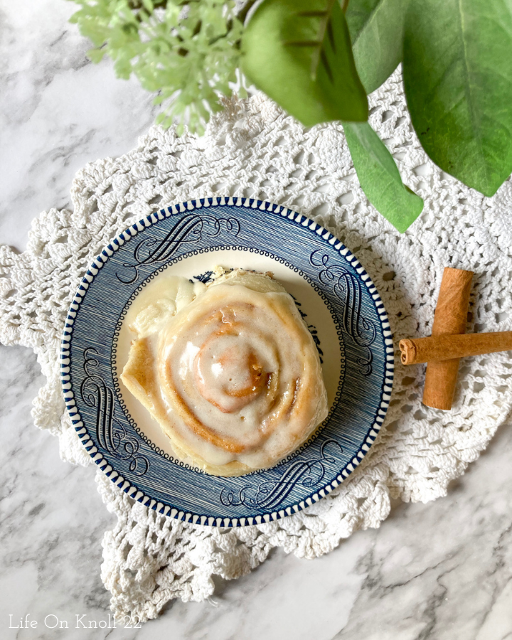 cinnamon roll on a plate with cinnamon sticks