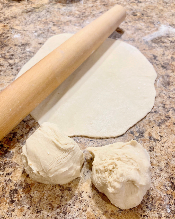 same day pizza dough rolled on the counter with a wooden rolling pin