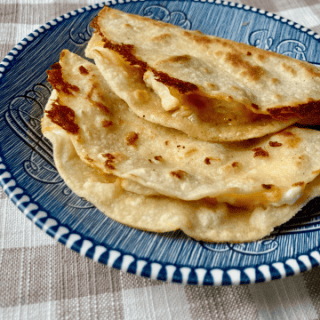 two crispy mini tacos on a blue plate atop a tan gingham tablecloth