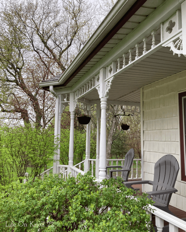 victorian wrap around porch with hanging flowers pots and rocking chairs