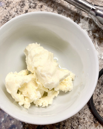 Butter from raw cream in a white ceramic bowl.