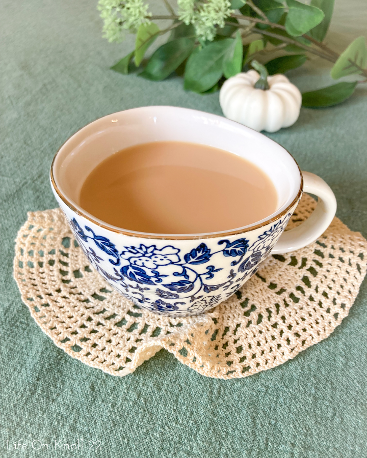 Cobalt and white mug with gold rim filled with vanilla honey tea and sitting on a doilie